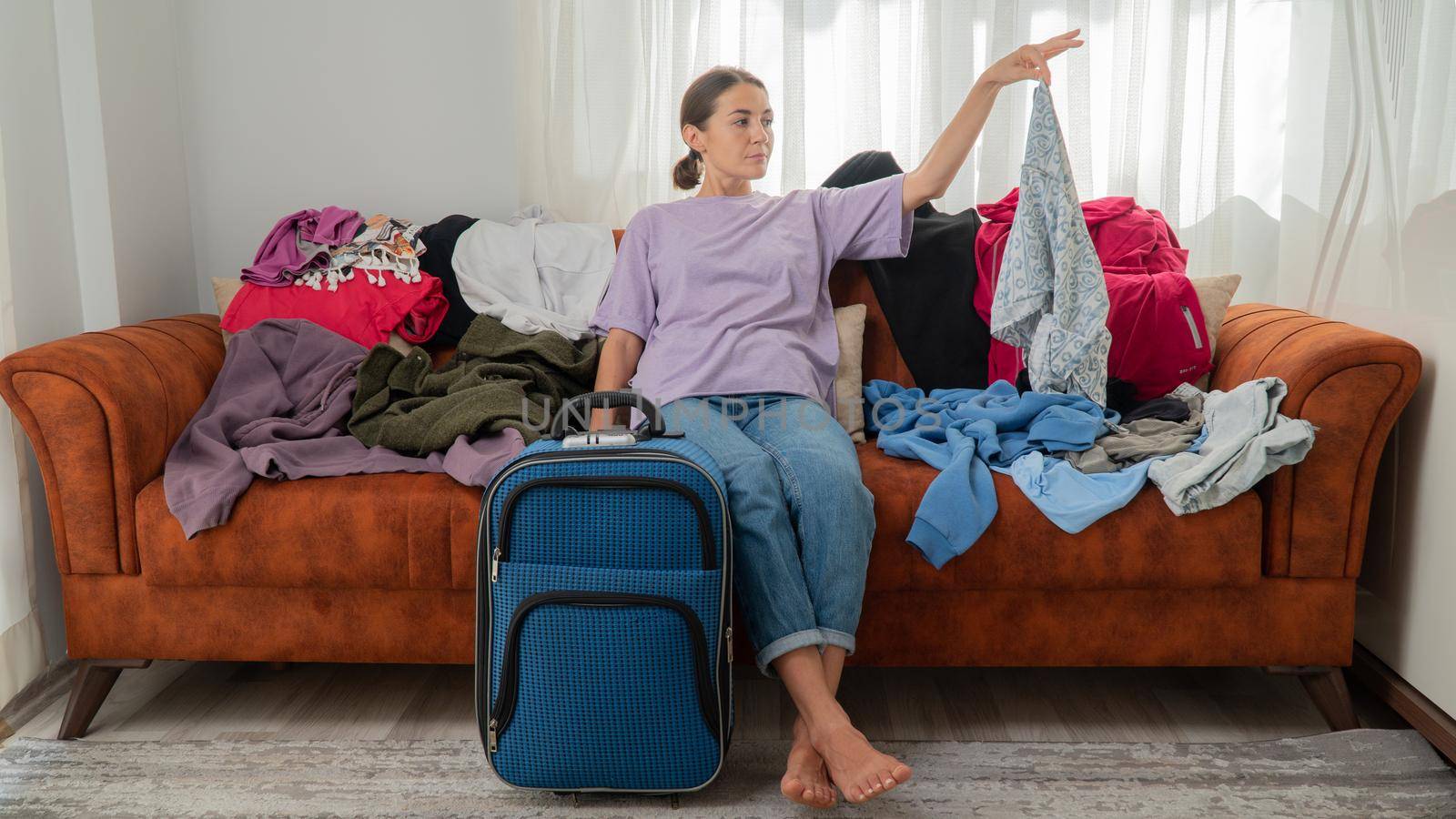 A woman packs a suitcase, decides what to take on a trip, a lot of clothes. High quality photo