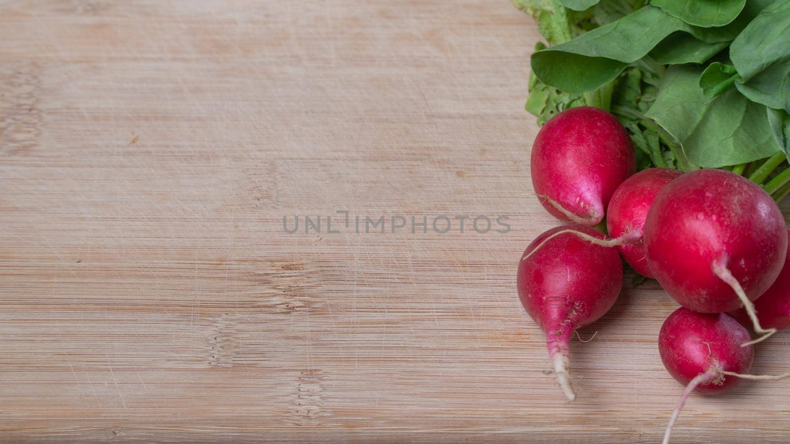 Radishes with leaves on a wooden board with space for inscription. High quality photo