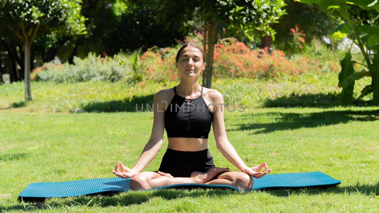 The girl does yoga in nature in the park, sits in the lotus position, breathing practice. High quality photo