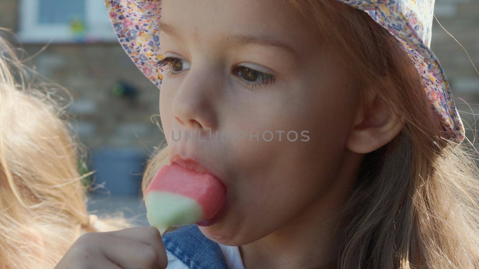 Close up portrait Girl enjoys delicious ice cream cone. Child eating watermelon popsicle. Kids Siblings snack sweets in Home Garden. Summer holiday Hot weather Sunny Day. Childhood, Food Candy Friends