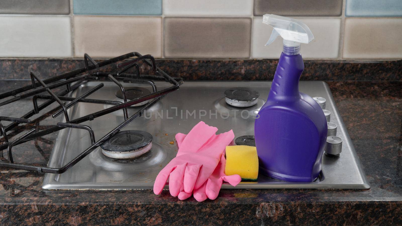 Washing kit rubber gloves, sponge, detergent on the gas stove in the kitchen
