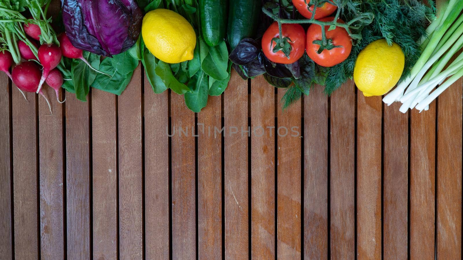 Vegetables and greens mix salad wooden background with space for inscription. High quality photo