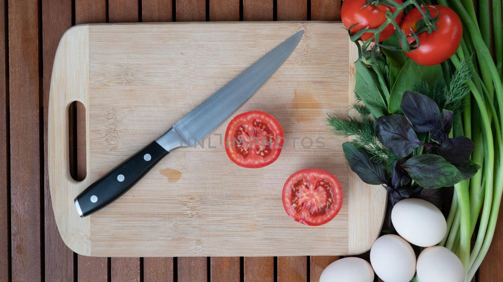 vegetables with a knife on a cutting board basil, green onions, eggs, tomato prepare salad