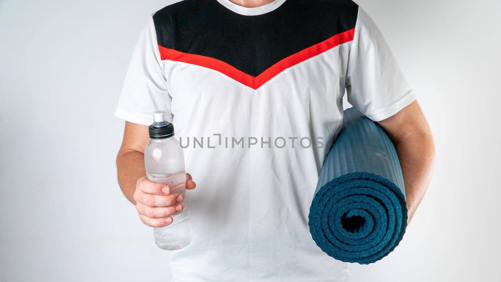 Sporty man with workout mat and bottle of water on white background by voktybre