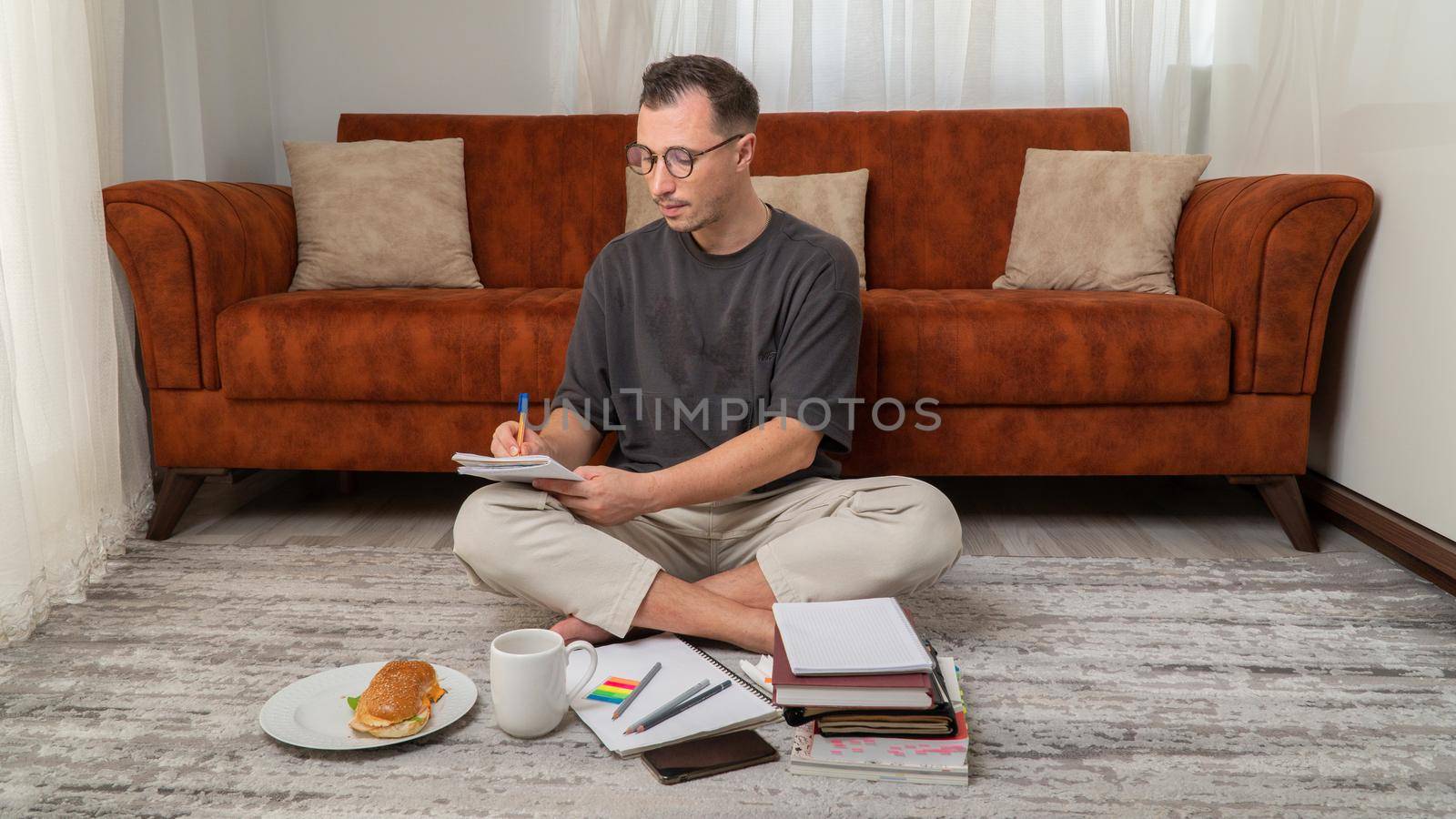 A guy student to study at home, writes in notebooks with books and textbooks. High quality photo