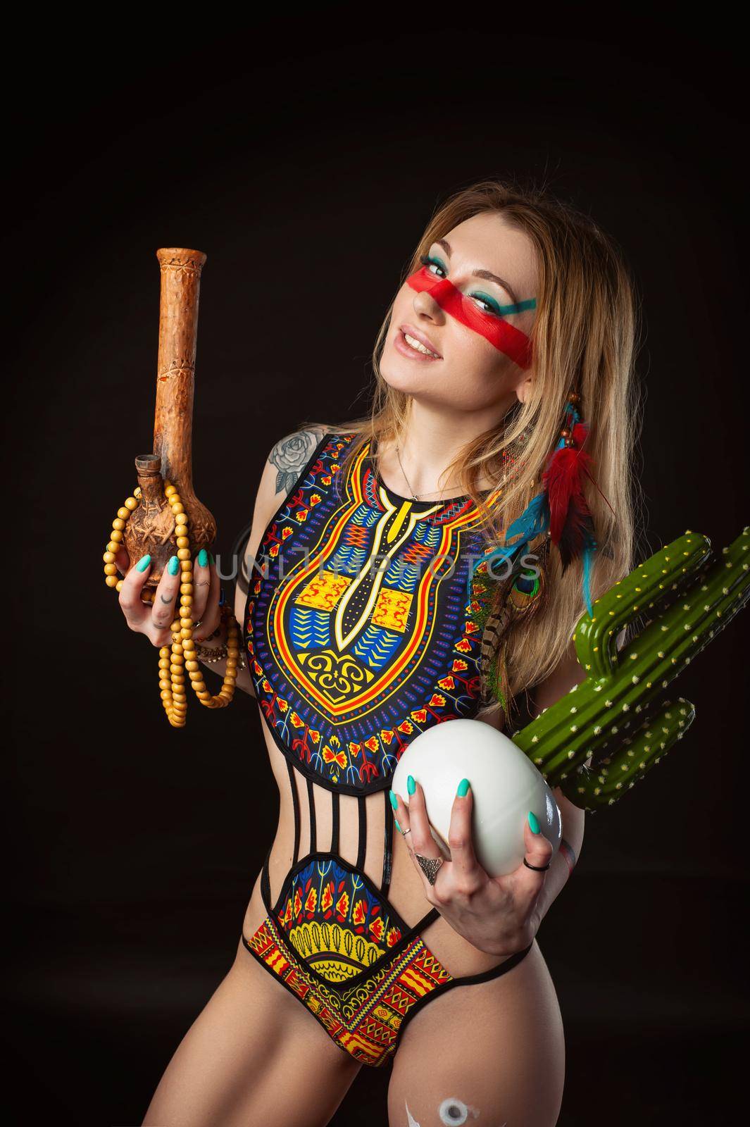 sexy hippie girl posing with bong for smoking marijuana in a bright swimsuit on a dark background by Rotozey