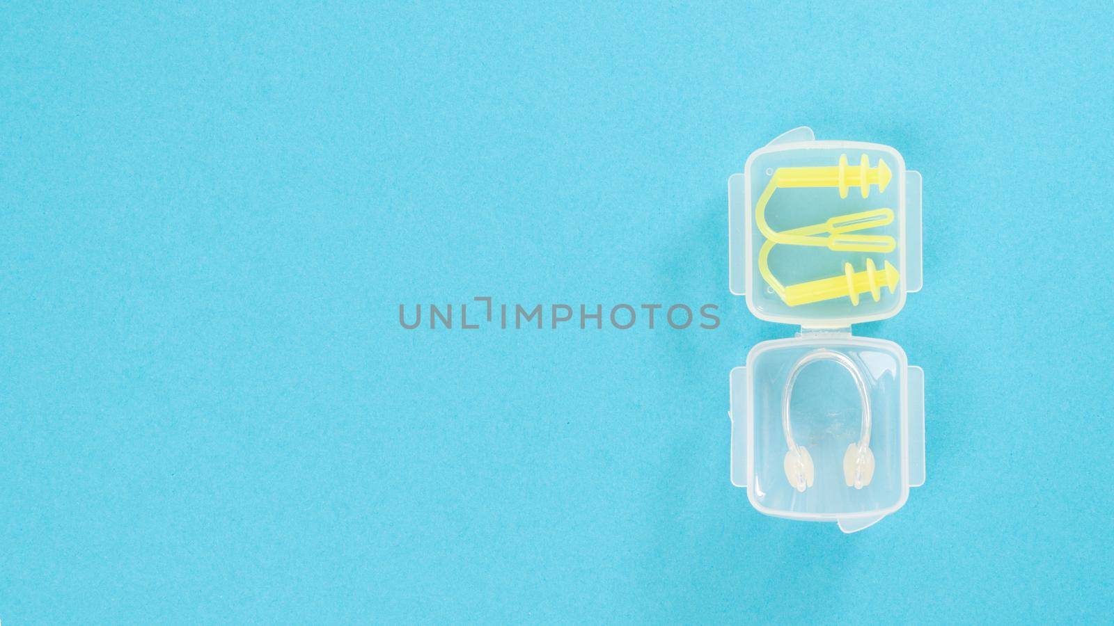 Nose clip and swimming earplug in a transparent case on a blue background by voktybre