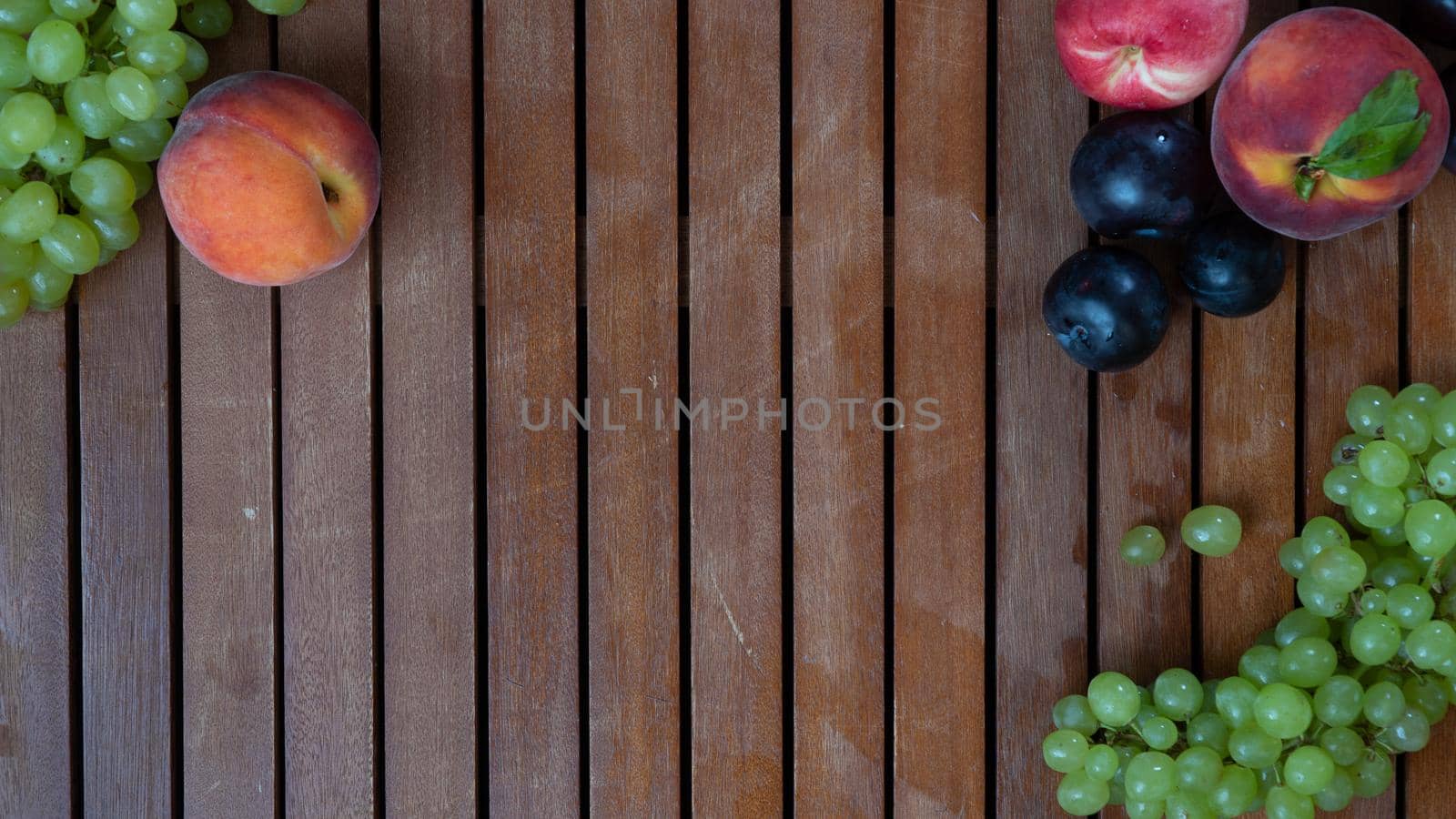 Fruits on a wooden background with space for inscription - grapes, peach, plum by voktybre