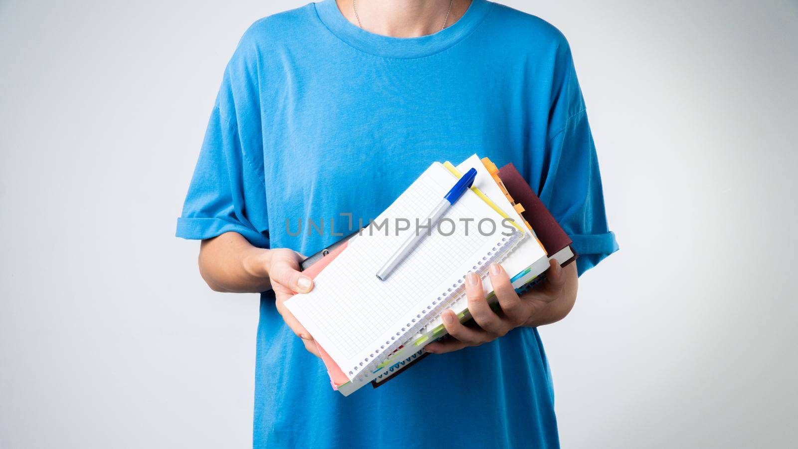 Women's hands hold notebooks, notepads, textbooks, books and a pen for studying by voktybre