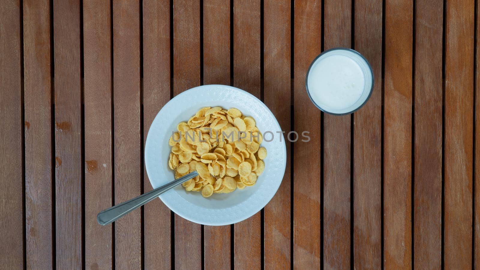 Corn flakes and milk for breakfast on a wooden background by voktybre