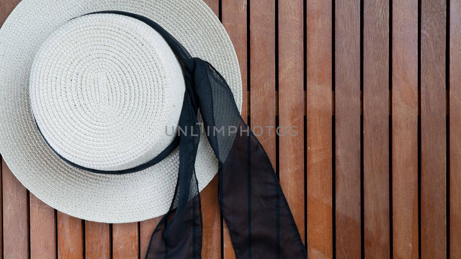 Straw women's hat with ribbon and glasses on a wooden background place for text