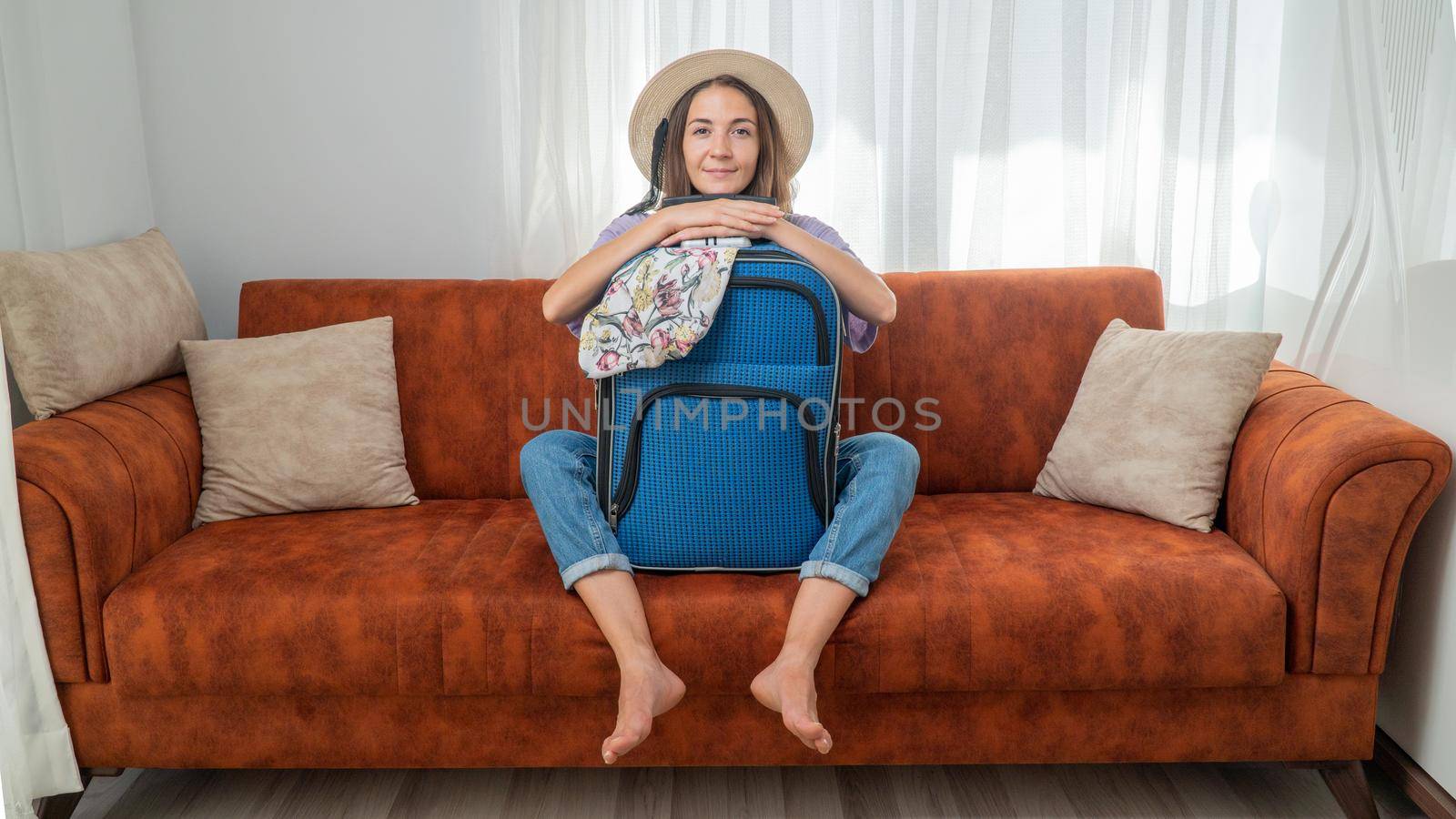 A satisfied woman with a packed suitcase on the couch, ready to travel. High quality photo