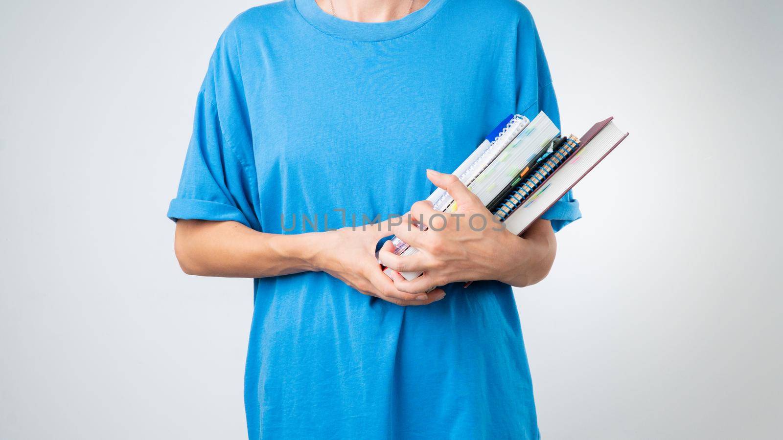 A student holds notebooks, books, a notebook, notebooks in her hands on a white background by voktybre