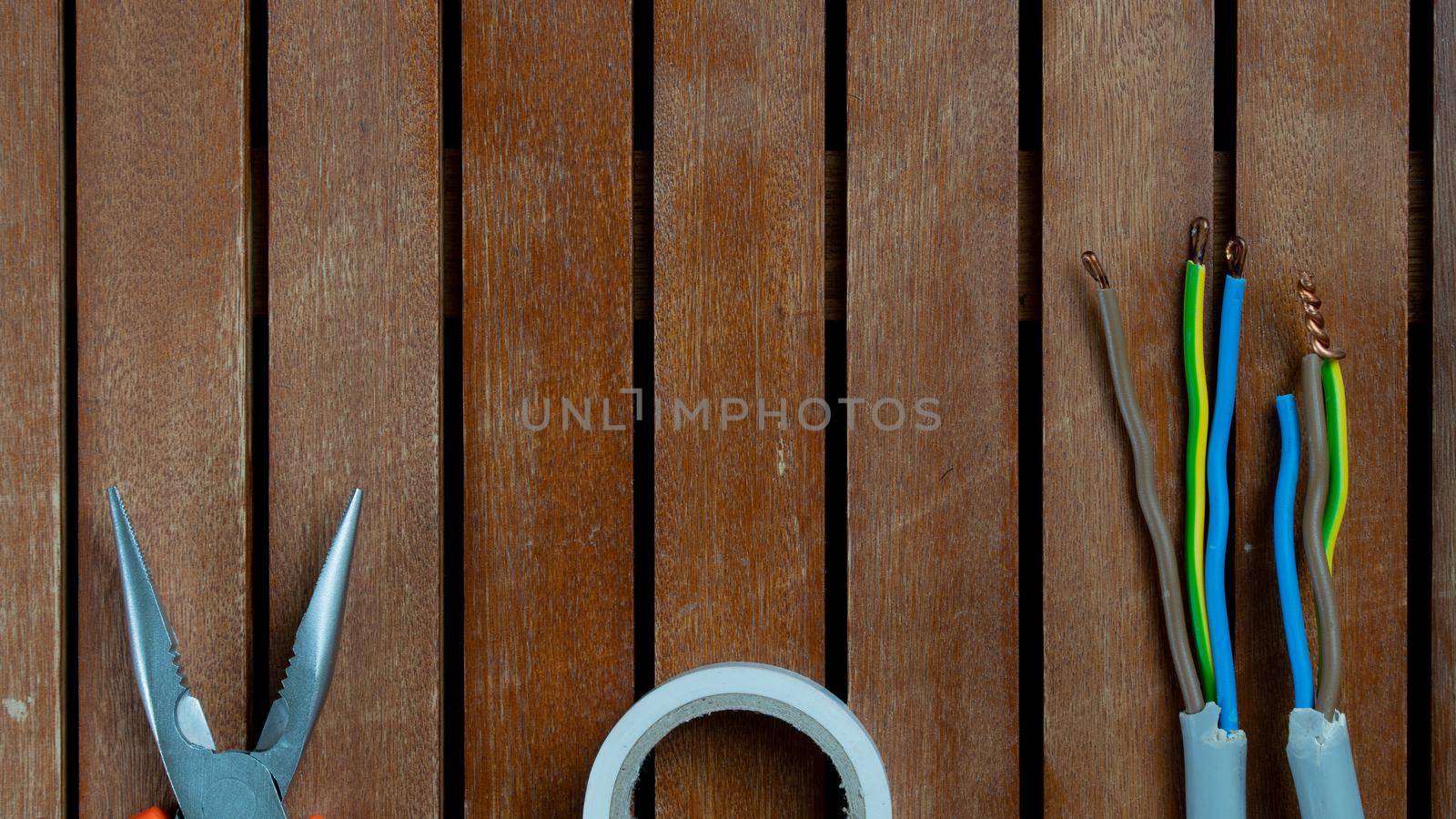 Wire cutters, duct tape and wires with free space for text background wooden boards. High quality photo