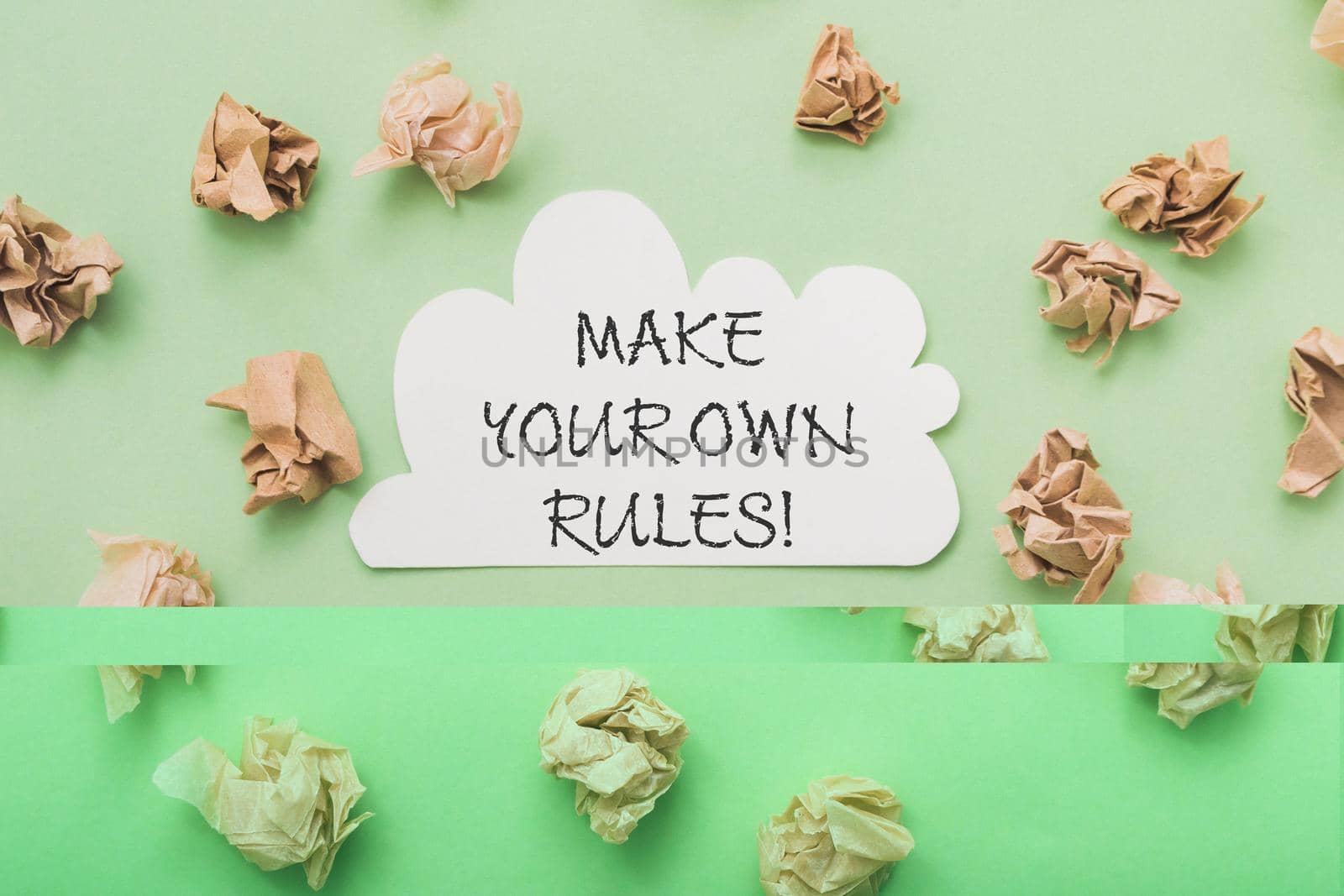 Phrase Make your Own Rules among scattered paper balls on light green background view from above. Create business plan. Independence and innovation