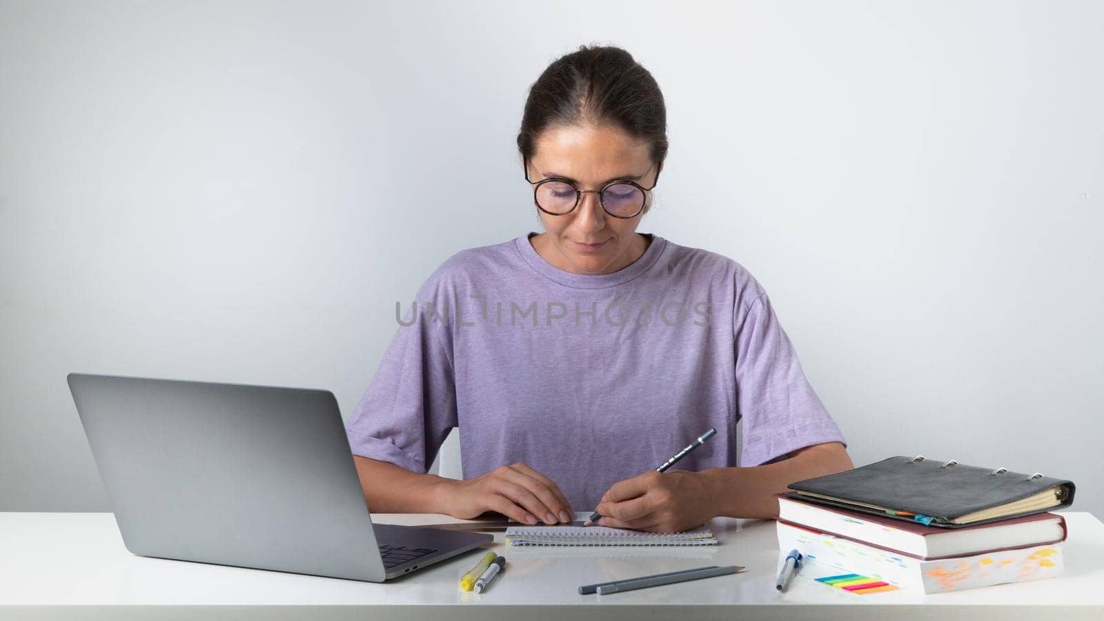The student draws with a pencil and a ruler, on the table a laptop, textbooks and notebooks. High quality photo