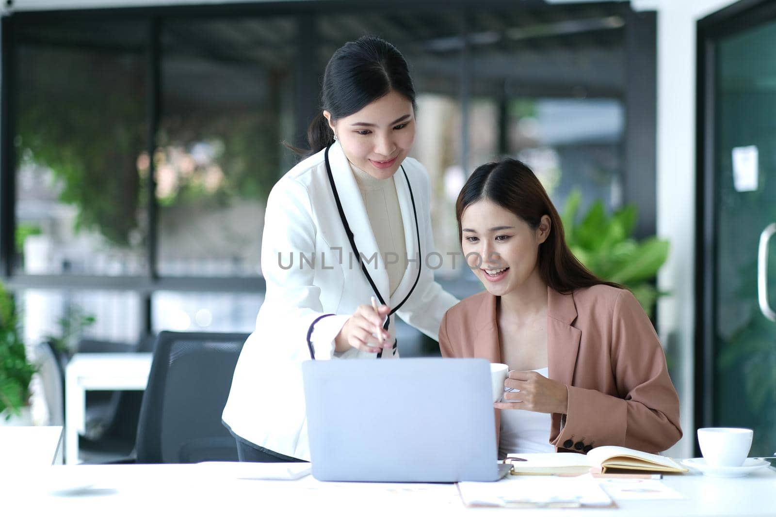 Two Young Asian businesswoman discuss with new startup project Idea presentation, analyze planning and financial statistics and investment market at office..