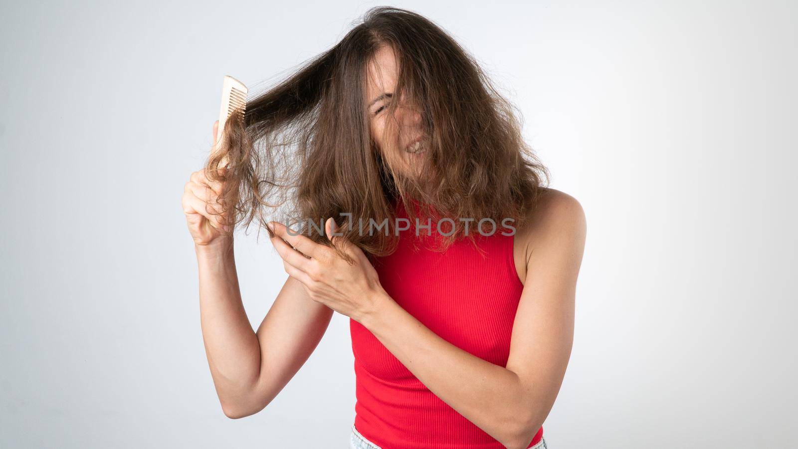 It hurts a woman when combing naughty, tangled hair - pulling out a comb and pulling her hair. High quality photo