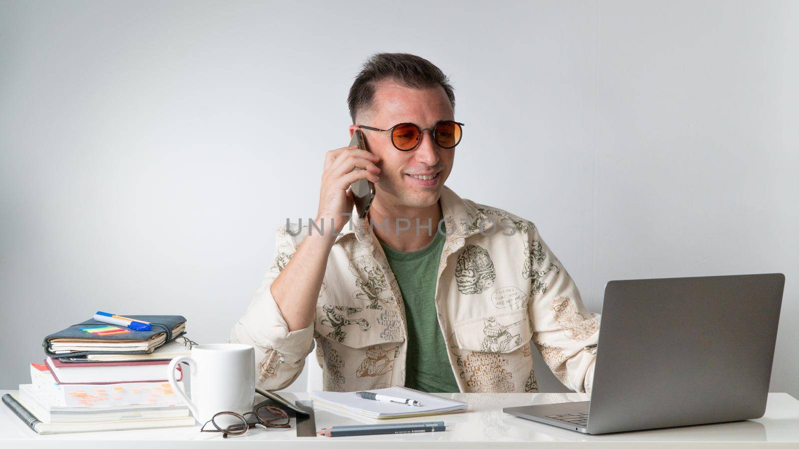 A student or employee talks on a smartphone at their desk. High quality photo