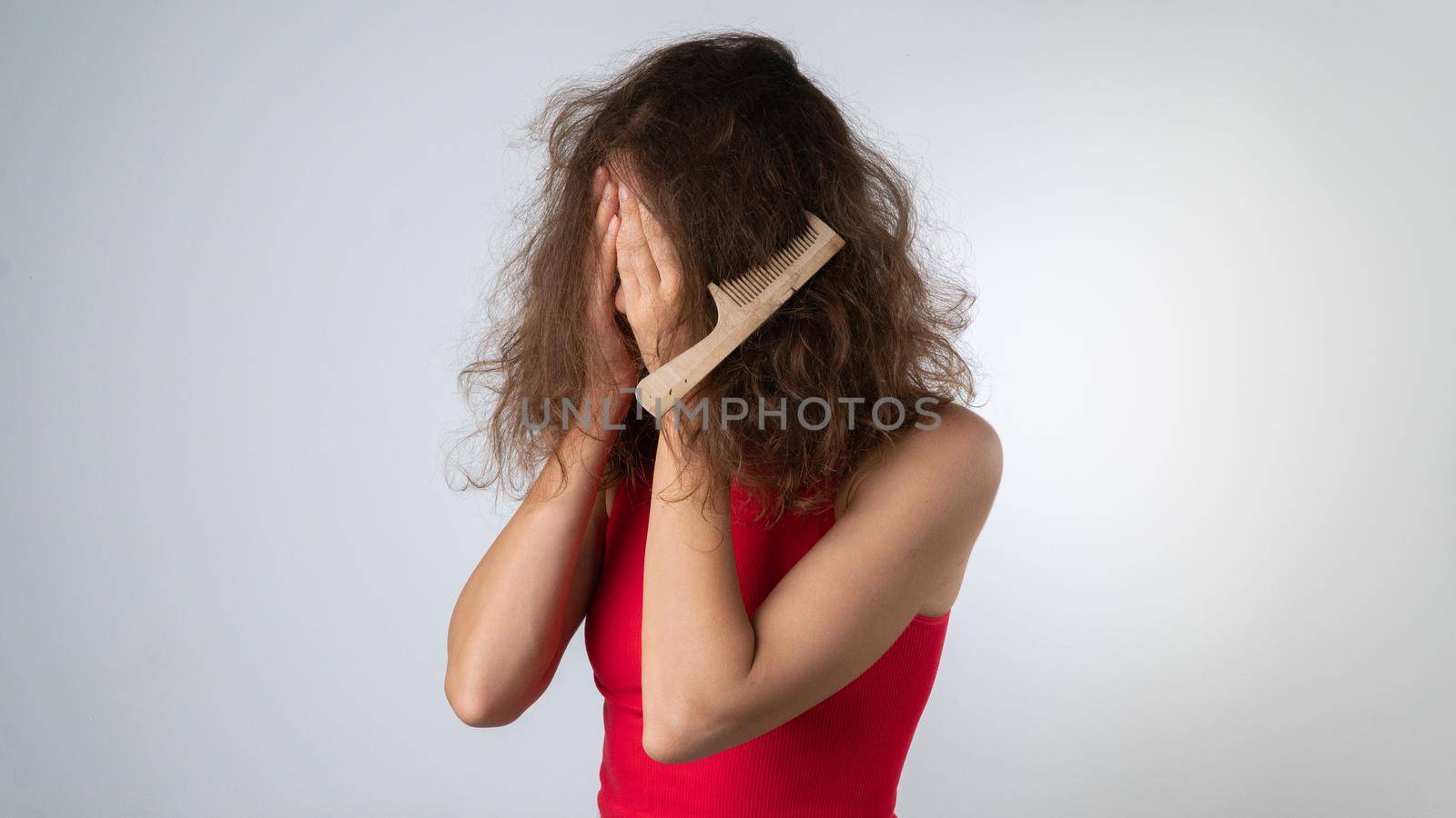 Upset woman with a tangled comb in her hair, problematic, naughty hair with split ends by voktybre