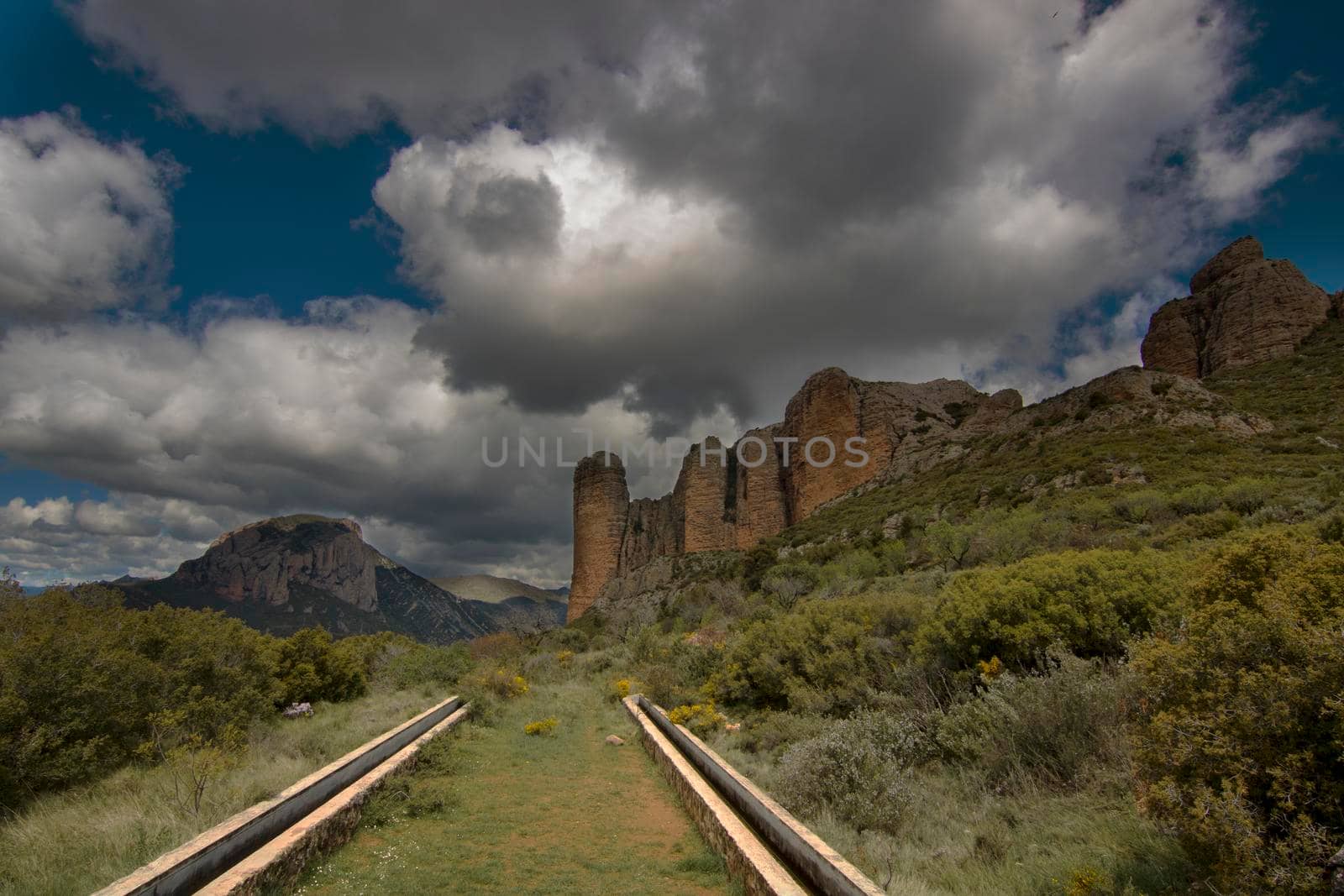 Vertical mountains called Mallos de Riglos under a cloudy sky in Huesca province in Spain