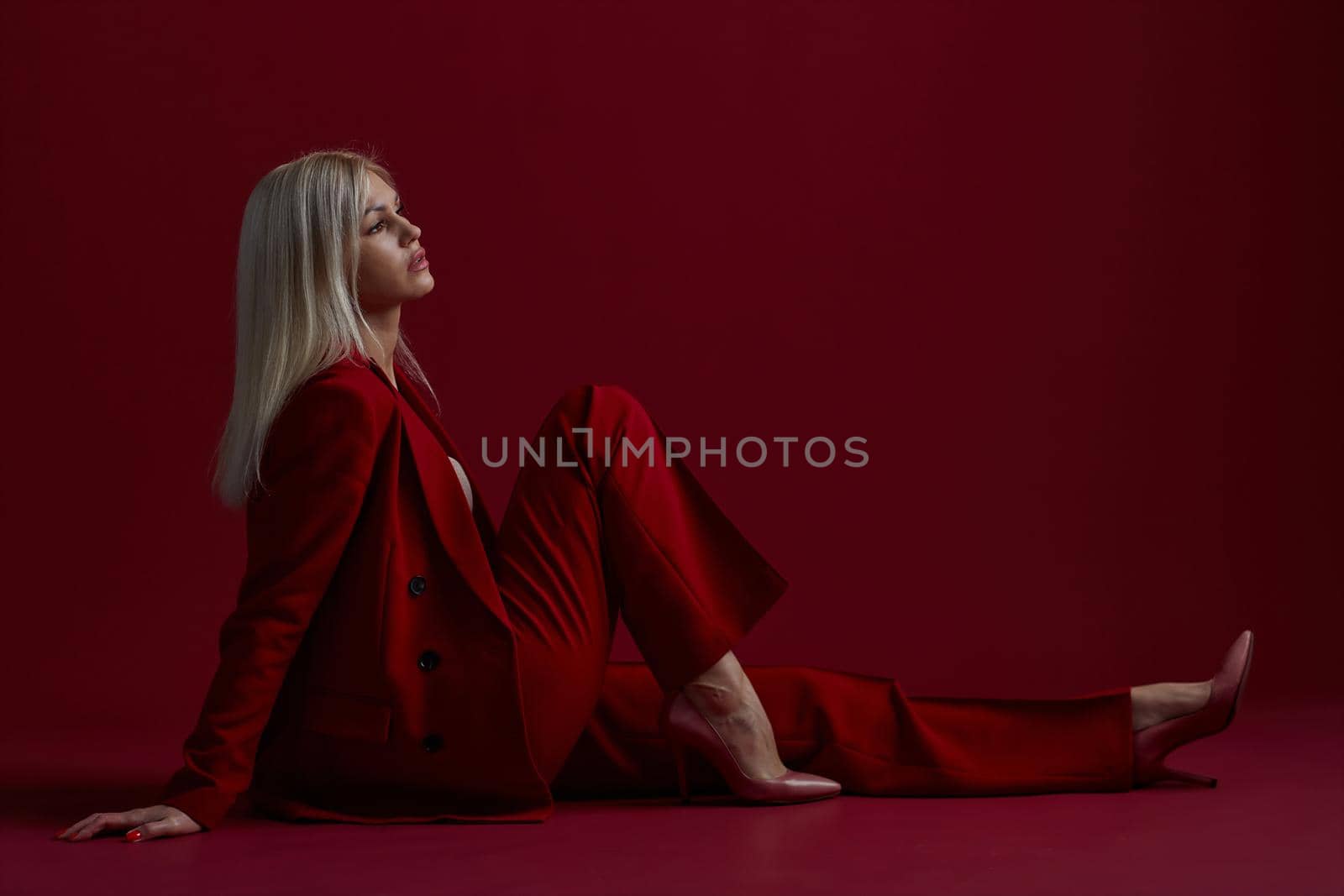 Portrait of a blonde woman in red dress on a red background