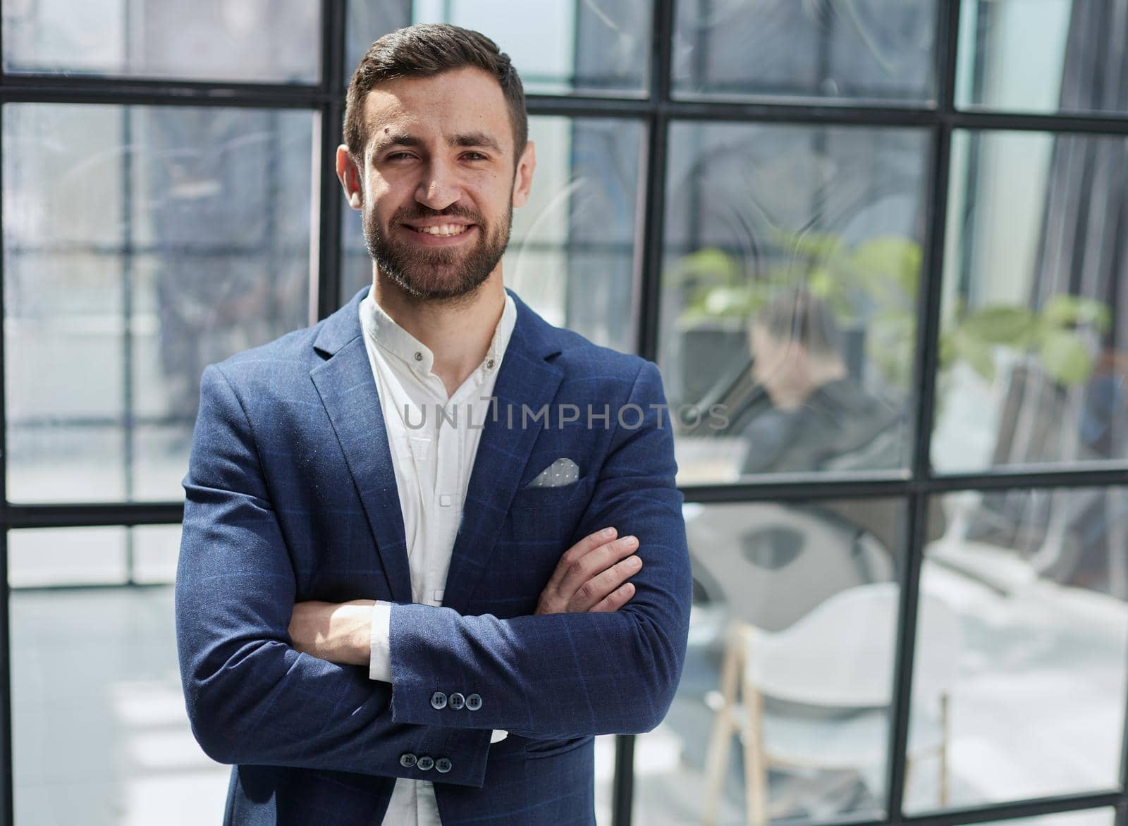 young businessman smiling in the office with his arms crossed