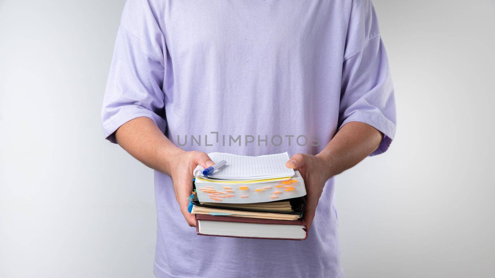 Male student holds a stack of notebooks and books on a white background. by voktybre