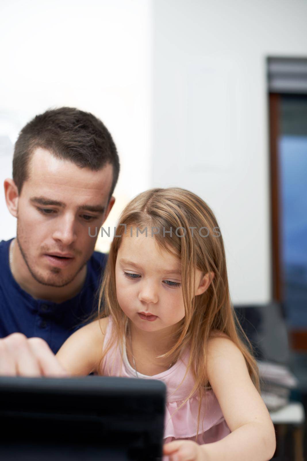 Sharing the wonders of technology with her. A father teaching his daughter how to use technology