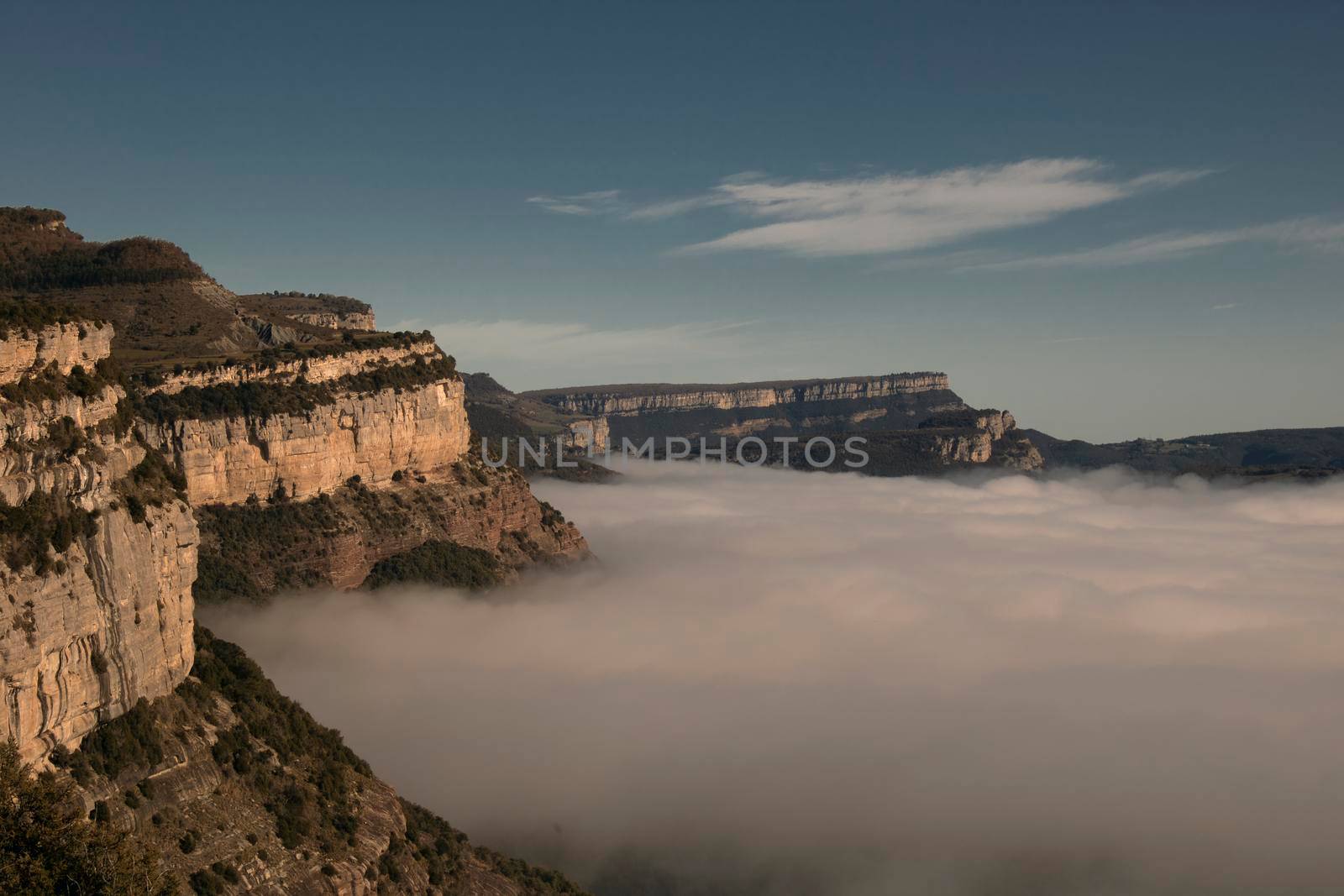Landscape partially covered by a layer of fog under a blue sky in Tavertet town in Catalonia