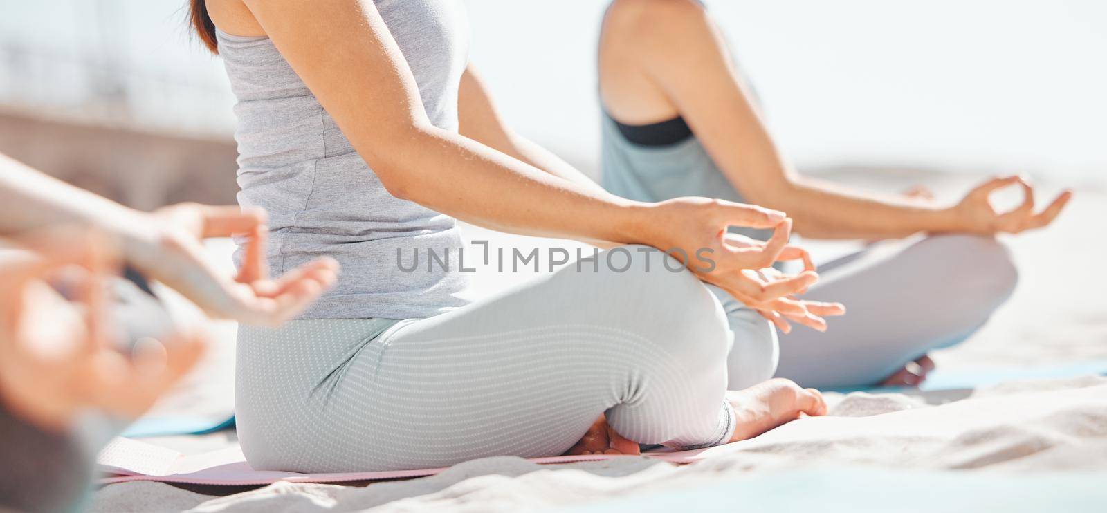 Women meditation in lotus with zen yoga class at the beach. Group of wellness female together on mat, leg crossed, finding inner mental balance and peace. Practice calming breathing exercise.