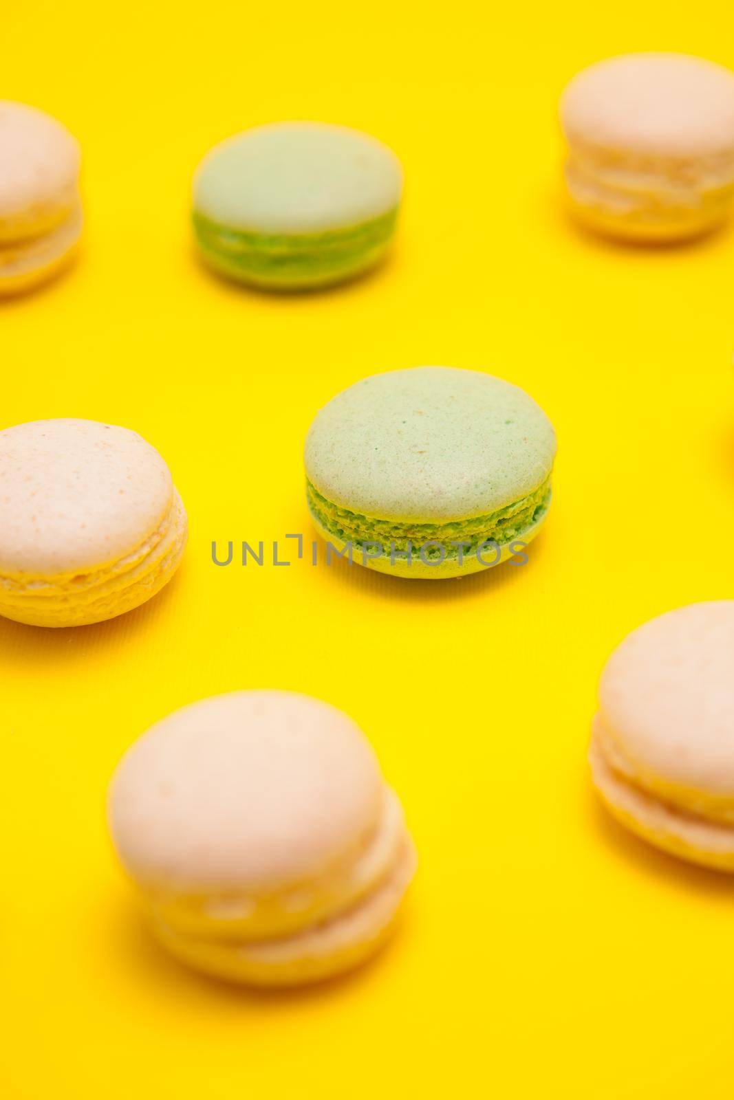 Little green tea macaroons and vanilla macaroons over yellow background