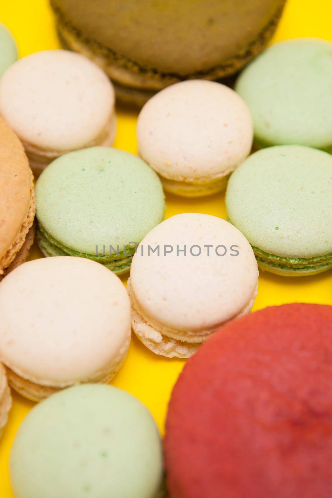 Big cherry macaroon flavour next to different macaroon flavours over yellow background. French dessert