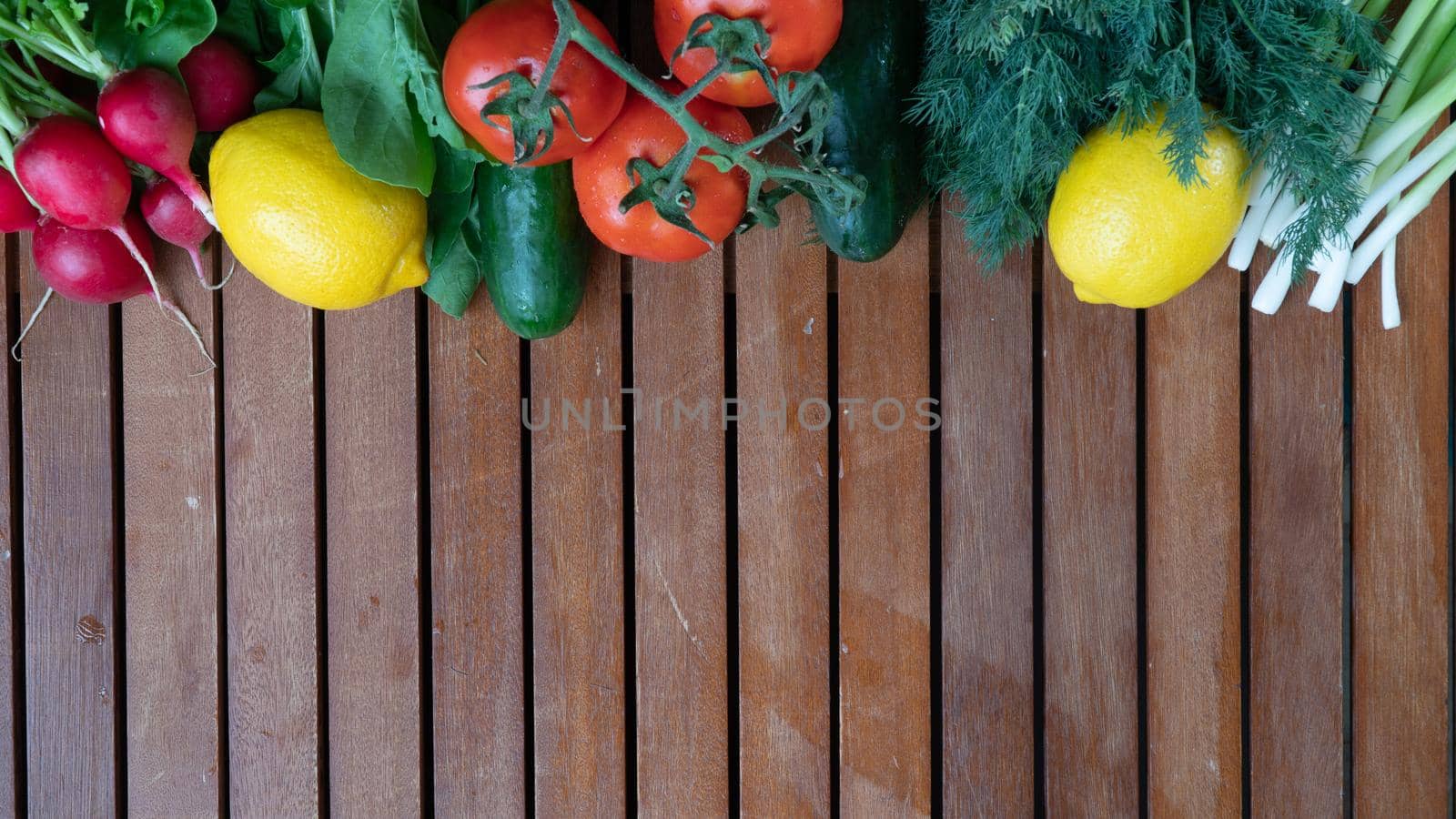 cucumbers, tomatoes, radishes, lemon and dill basil greens and green onions on a flat wooden background by voktybre