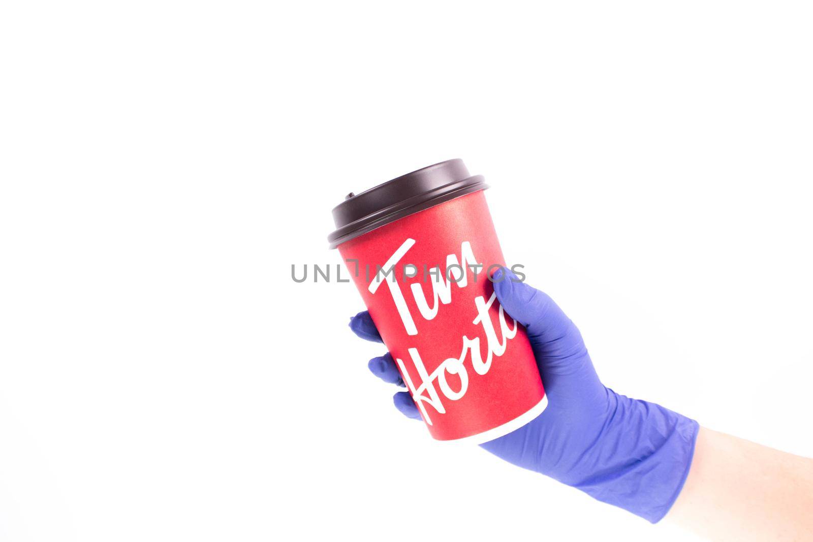 Nurse hand in medical glove holding a Tim Hortons Large Cup of Coffee. Red Tims coffee cup. Gatineau, Quebec, Canada August 4, 2022.