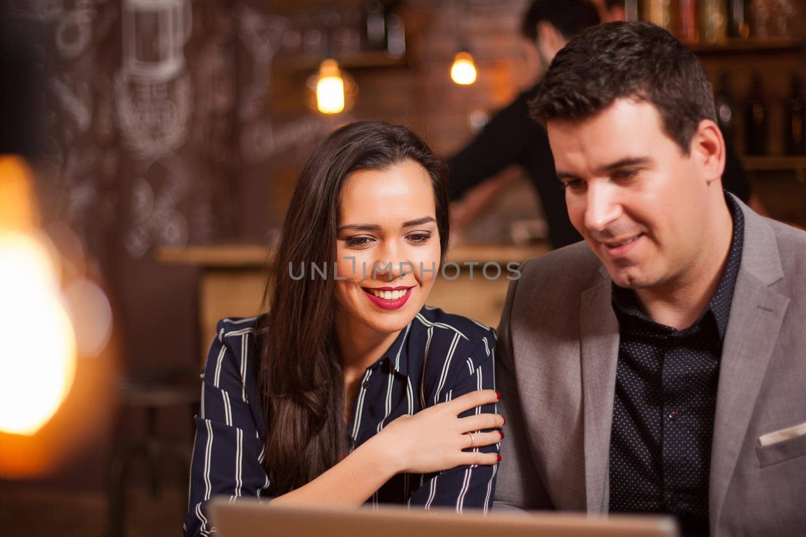 Smiling girl and her business partner having a video call in a coffee shop. by DCStudio