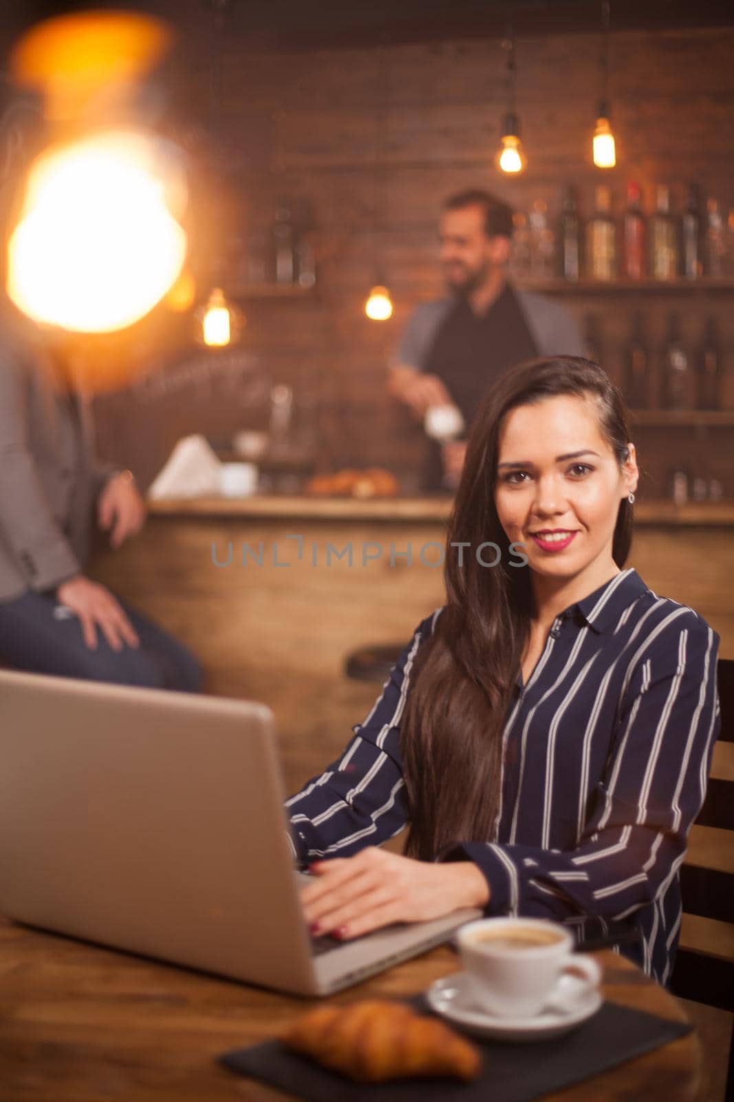 Portrait of a young woman working on her laptop in a coffee shop by DCStudio