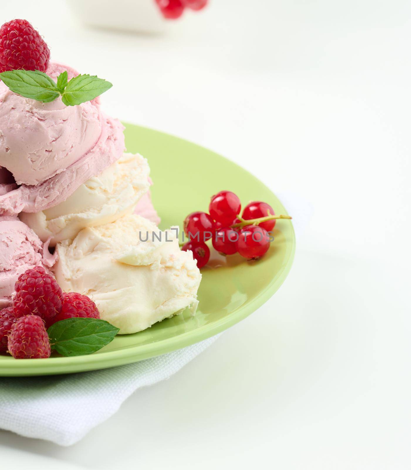 Vanilla and raspberry ice cream scoops on a round green plate by ndanko