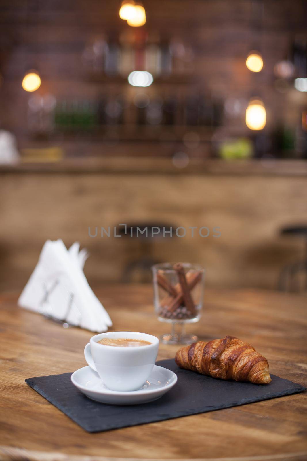 Hot coffee and croissant on coffee shop wooden table. Coffee aroma. Knapkins