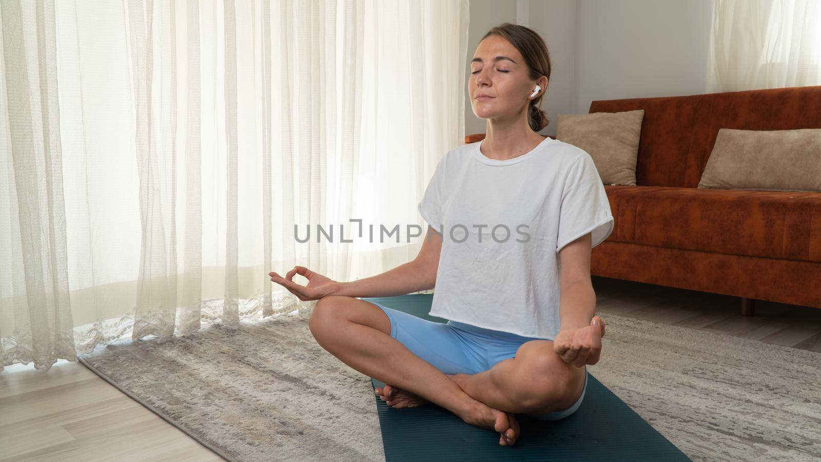 A woman meditates at home in the lotus position on a yoga mat. High quality photo