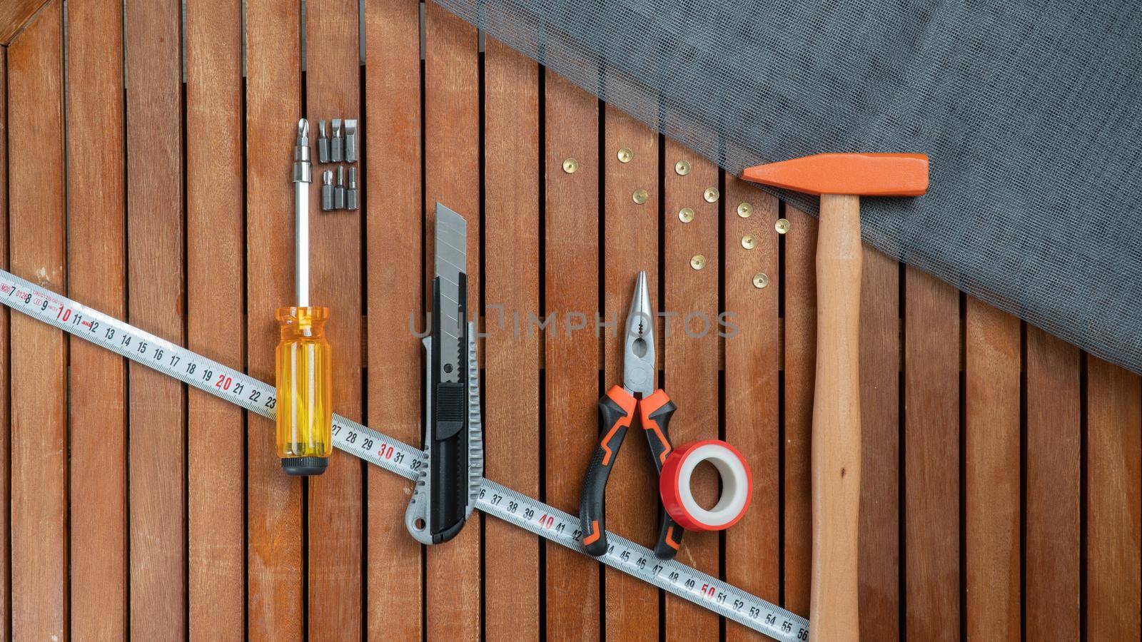 Tool set - hammer, wire cutters, centimeter, screwdriver, construction net, stationery knife on a wooden background by voktybre