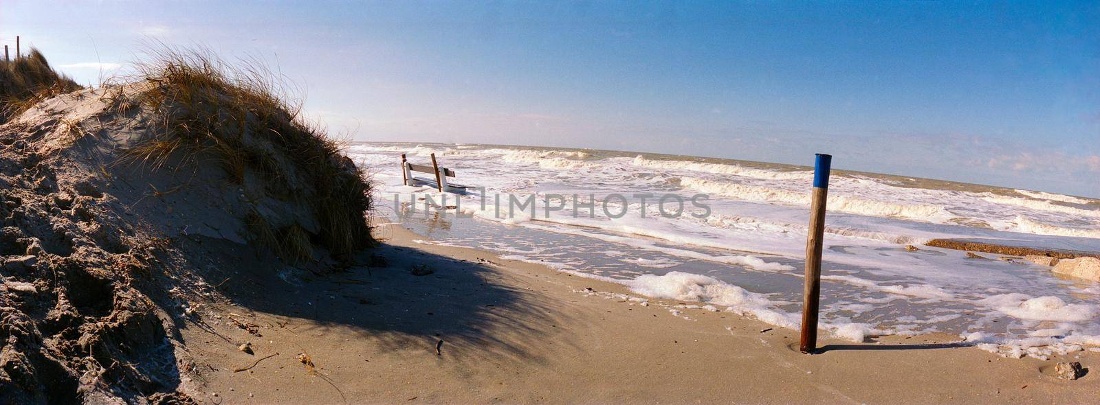 panorama of a bench in a rising sea with a sanddune