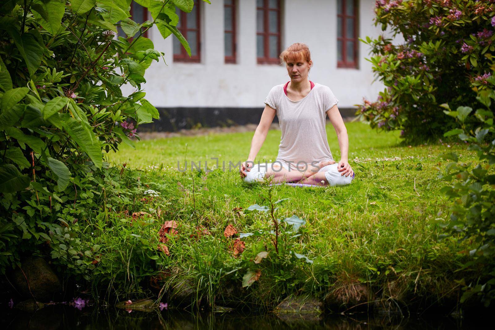 Contemplation and nature. a woman sitting in the lotus position in her backyard. by YuriArcurs