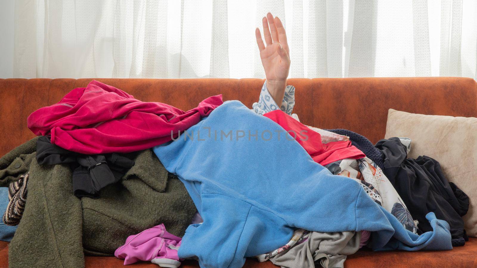 A hand reaches up from a pile of clothes, a shopaholic addiction. High quality photo