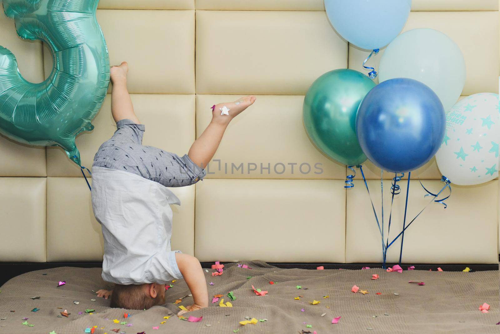 Boy rejoices with confetti and balloons for his birthday Boy upside down for his birthday
