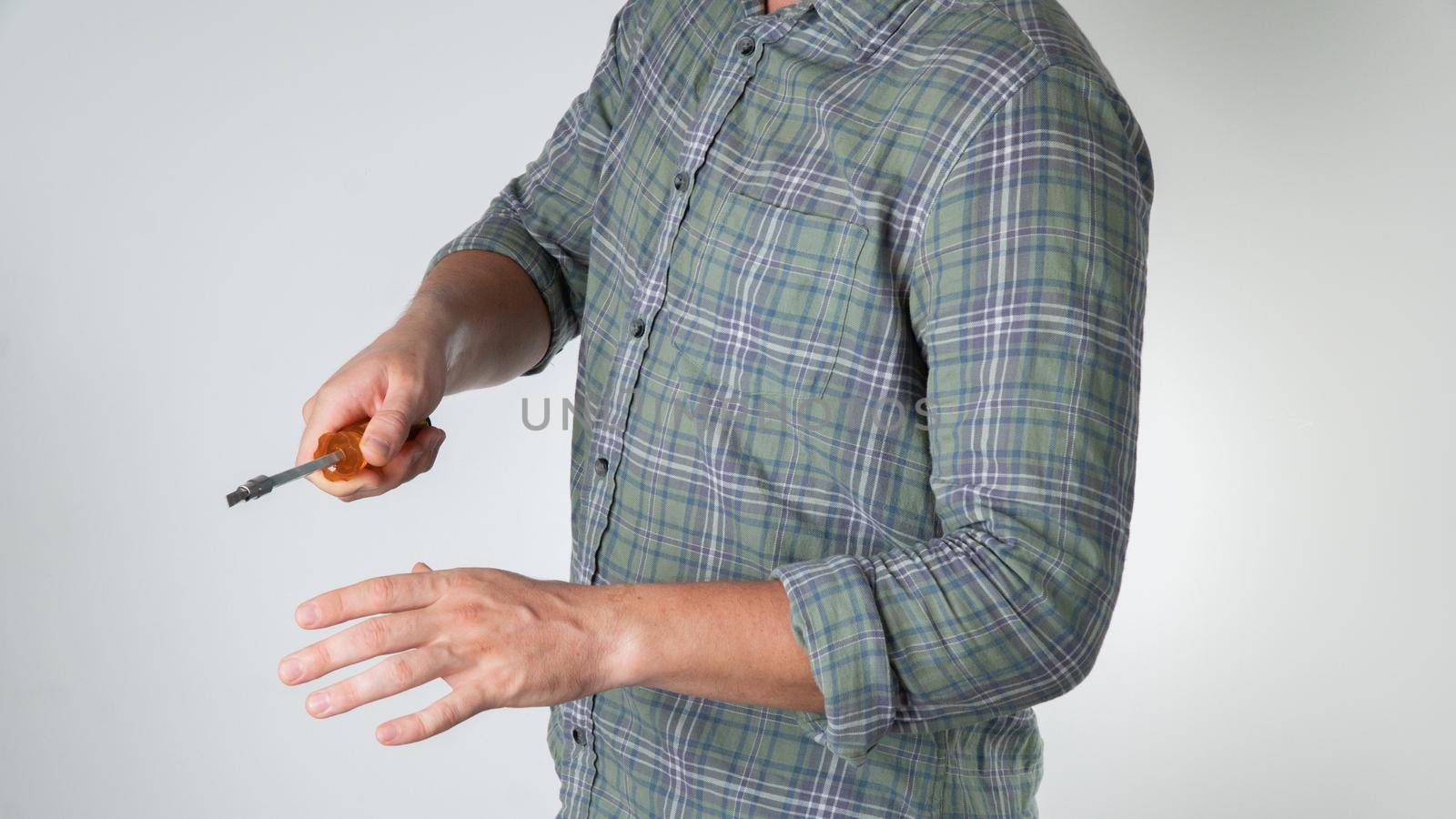 A man with a screwdriver in his hand gesture screws a close-up screw on a white background. High quality photo