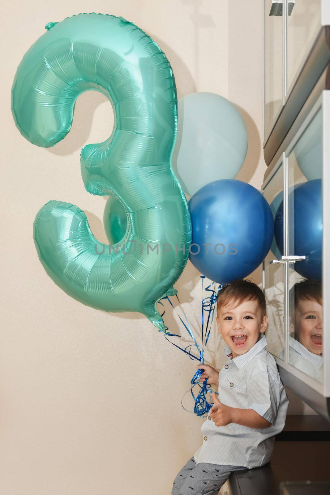 Boy with the number three and the ballons for his birthday at home