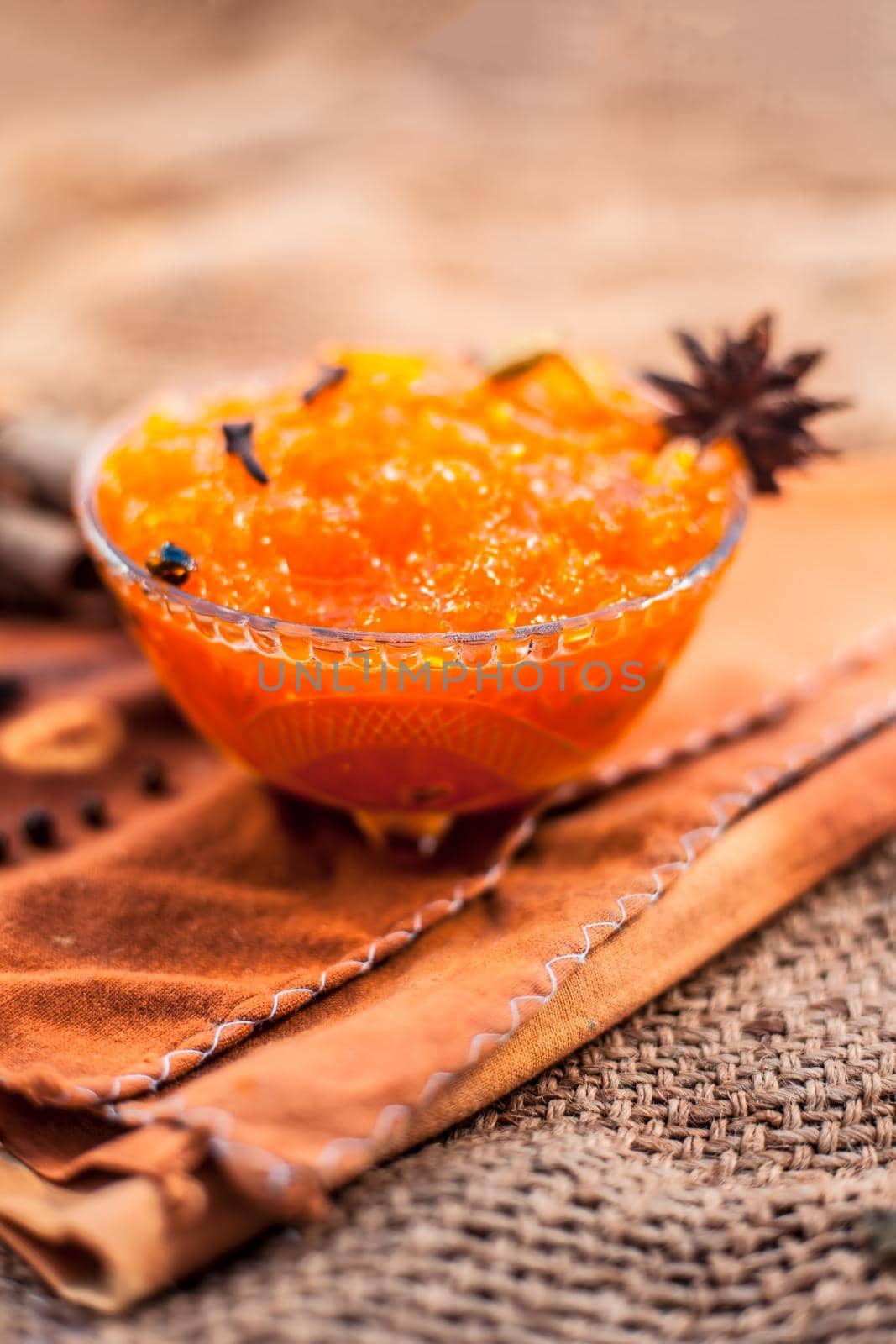 Famous Indian dessert and sweet dish in a glass bowl on jute bag's surface i.e. Murabba or Murba along with entire constituents of it on the surface.Made of Mango.Vertical shot.