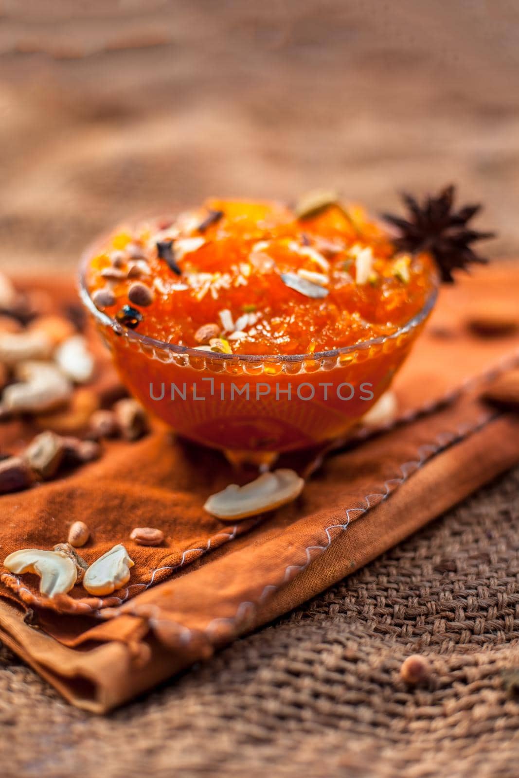 Famous mango preservation i.e. Murba or Murabba in a glass bowl on jute bag's surface along with dry fruits and spcies with it.Horizontal shot with background blurred. by mirzamlk