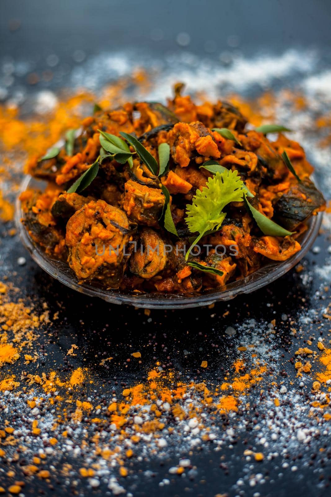 Famous Indian & Gujarati snack dish in a glass plate on wooden surface i.e. Patra or paatra consisting of mainly Colocasia esculenta or arbi ke pan or elephant ear leaves and spices. Vertical shot. by mirzamlk